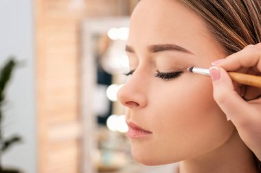 Salonda, closeup kadının yüzüne makyaj uygulayarak profesyonel visage sanatçı
