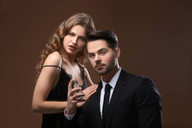 Tutkulu kadın ve renk arka plan üzerinde parfüm kullanan yakışıklı adam