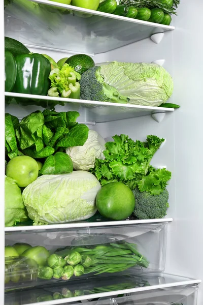 Diferentes verduras y frutas verdes en los estantes del refrigerador — Foto de Stock