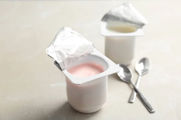 Vasos de plástico con diferentes yogures sobre fondo claro — Foto de Stock
