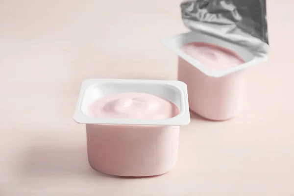 Plastic bekers met yummy yoghurt op houten tafel — Stockfoto