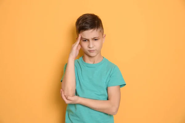 Little boy suffering from headache on color background — Stock Photo, Image