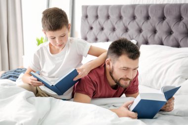 Küçük bir çocuk ve babası yatak odasında kitap okuma