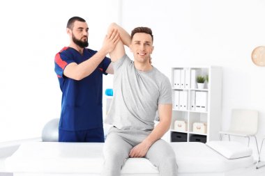 Fizyoterapist klinikte genç erkek hasta ile çalışma