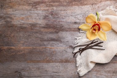 Vanilya çubukları ve çiçek ahşap arka plan, üstten görünüm