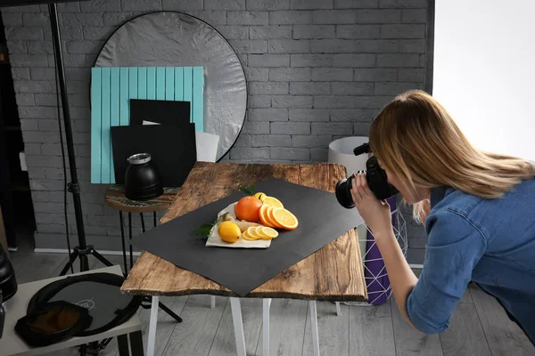 Mulher tirando foto de comida com câmera profissional em estúdio — Fotografia de Stock