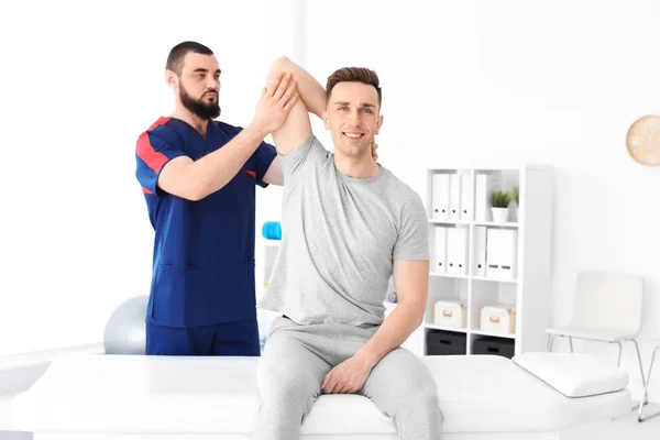 Physiotherapist working with young male patient in clinic — Stock Photo, Image