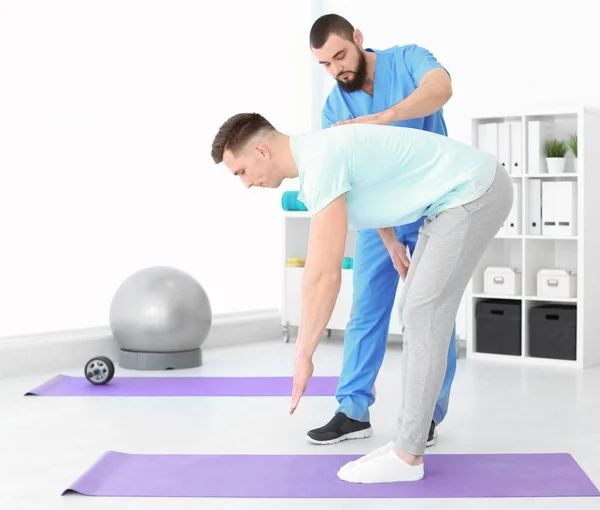 Physiotherapist working with young male patient in clinic — Stock Photo, Image