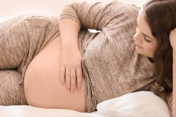 Young pregnant woman lying on bed at home — Stock Photo, Image