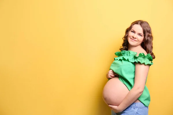 Молодая беременная женщина в повседневной одежде на цветном фоне — стоковое фото