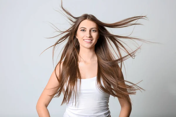 Porträtt av ung kvinna med långa vackra hår på ljus bakgrund — Stockfoto