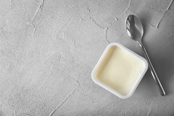 Plastmugg med läckra yoghurt på grå bakgrund, ovanifrån — Stockfoto