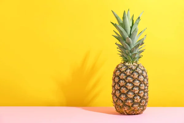 Свежий ананас на столе против цветной стены — стоковое фото