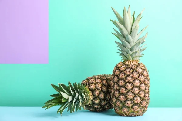 Piñas frescas en la mesa contra la pared de color — Foto de Stock