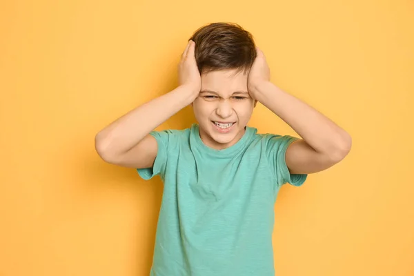 Niño que sufre de dolor de cabeza en el fondo de color — Foto de Stock