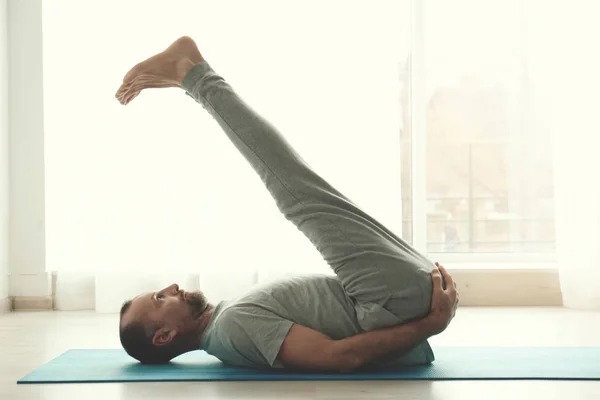 Homem desportivo praticando ioga dentro de casa — Fotografia de Stock