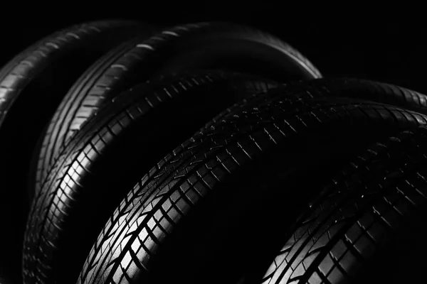 Нові автомобільні шини на чорному тлі, крупним планом — стокове фото