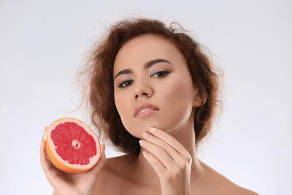 Mooie jonge vrouw met acne probleem bedrijf grapefruit op lichte achtergrond. Allergie huid — Stockfoto