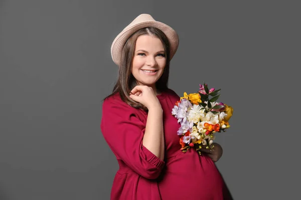 Красива вагітна жінка з квітами на кольоровому фоні — стокове фото