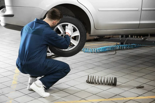 Joven mecánico cambiando de rueda en el servicio de neumáticos — Foto de Stock