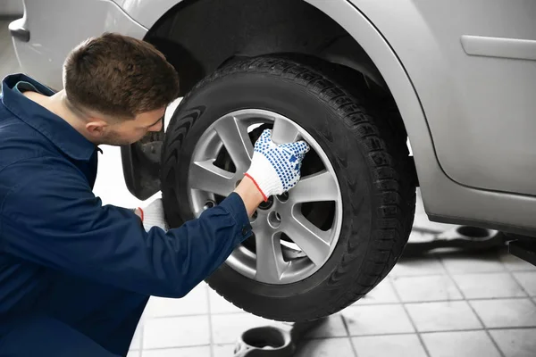 Joven mecánico cambiando de rueda en el servicio de neumáticos — Foto de Stock