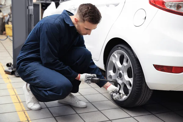 Jovem mecânico verificar a pressão do pneu no centro de serviço — Fotografia de Stock