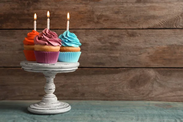 Stand mit leckeren Geburtstagskuchen mit brennenden Kerzen auf dem Tisch — Stockfoto