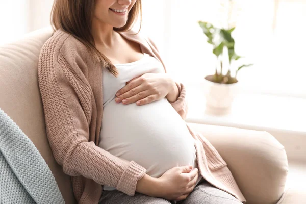 Jonge zwangere vrouw zittend op de bank in de woonkamer — Stockfoto