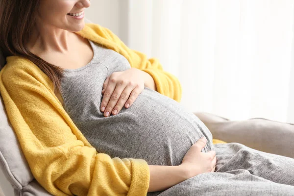 Jonge zwangere vrouw rusten in fauteuil thuis — Stockfoto