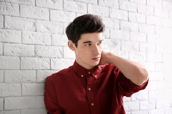 Portrait de jeune homme avec de beaux cheveux sur fond de mur de briques — Photo