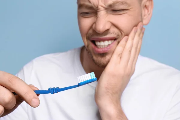 Młody człowiek cierpi na ból zęba na szarym tle — Zdjęcie stockowe