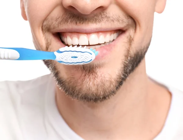Young man brushing his teeth on white background — Stock Photo, Image
