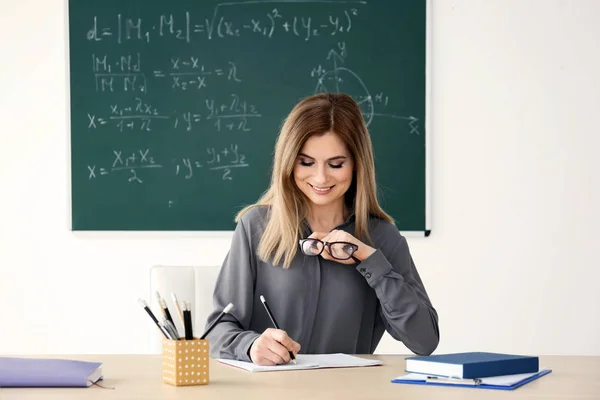 Jovem professora que trabalha à mesa em sala de aula — Fotografia de Stock