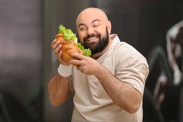 Överviktig man äta smörgås i gymmet — Stockfoto