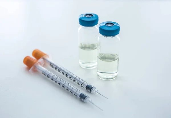 Φιαλίδια με φάρμακα και σύριγγες επάνω ελαφρύς υπόβαθρο. Έννοια του εμβολιασμού — Φωτογραφία Αρχείου