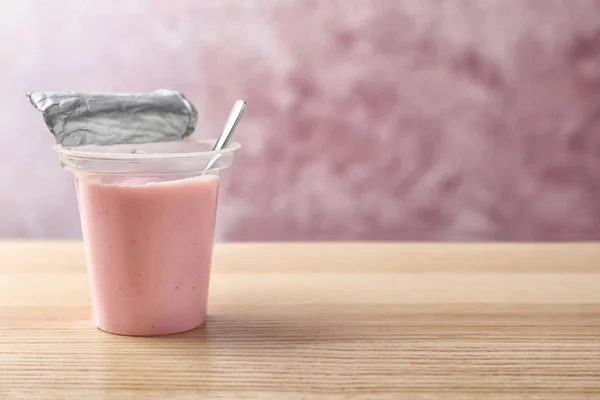 Copa de plástico con sabroso yogur en la mesa de madera — Foto de Stock