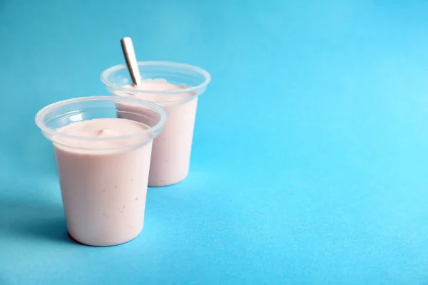 Tasses en plastique avec yaourt savoureux sur fond de couleur — Photo