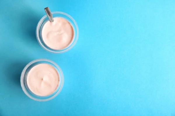 Bicchieri di plastica con gustoso yogurt su sfondo colore, vista dall'alto — Foto Stock