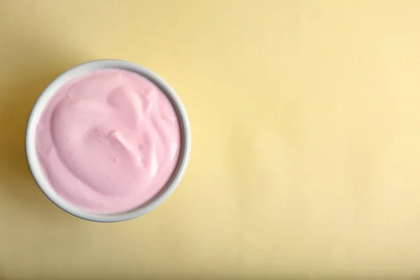 ถ้วยที่มีโยเกิร์ตอร่อยบนพื้นหลังสี, มุมมองด้านบน — ภาพถ่ายสต็อก