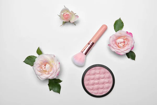Flat lay composition with makeup brush, powder and flowers on white background