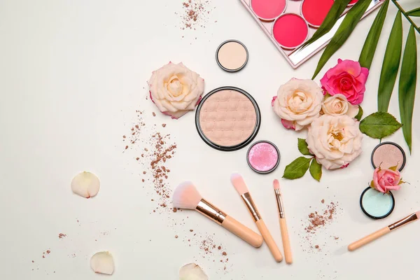 Composición plana con pinceles de maquillaje, productos cosméticos y flores sobre fondo blanco — Foto de Stock