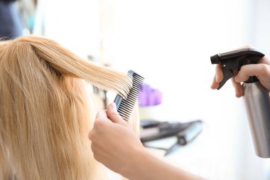 Profesyonel kuaför müşteriyle kuaförde çalışıyor.