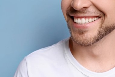 Genç adam gri arka plan üzerinde güzel gülümseme. Diş beyazlatma