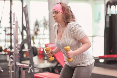 Kilolu kadın spor salonunda dumbbells ile eğitim