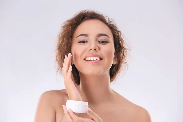 Mooie jonge vrouw met een probleem huid anti acne crème op lichte achtergrond toepassen — Stockfoto