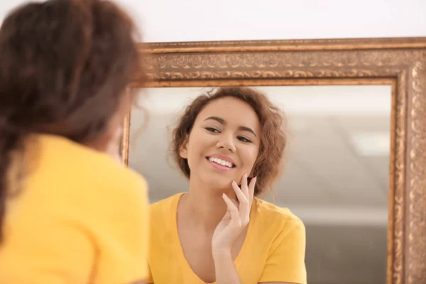 Mooie jonge vrouw met acneprobleem kijken in de spiegel thuis — Stockfoto