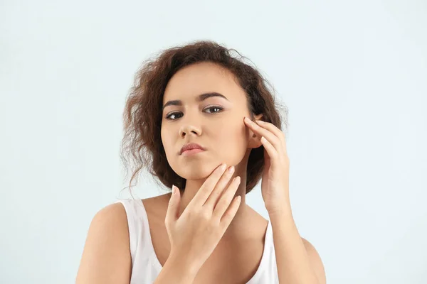 Mooie jonge vrouw met acneprobleem op lichte achtergrond — Stockfoto
