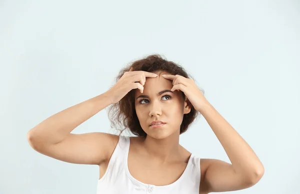 Mooie jonge vrouw met acneprobleem op lichte achtergrond — Stockfoto