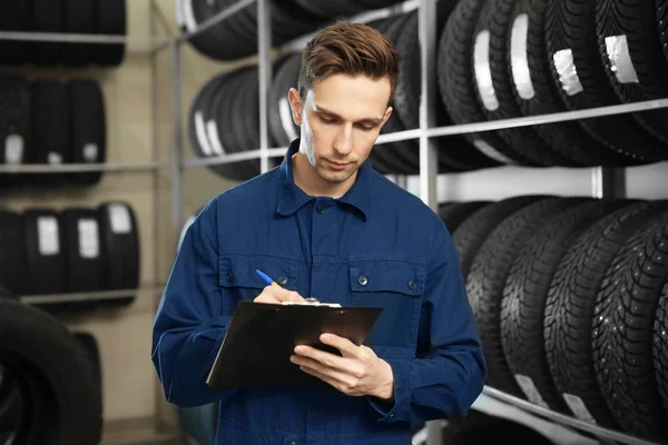 Mladý muž mechanik s schránky u pneumatiky v automobilovém servisní centrum — Stock fotografie