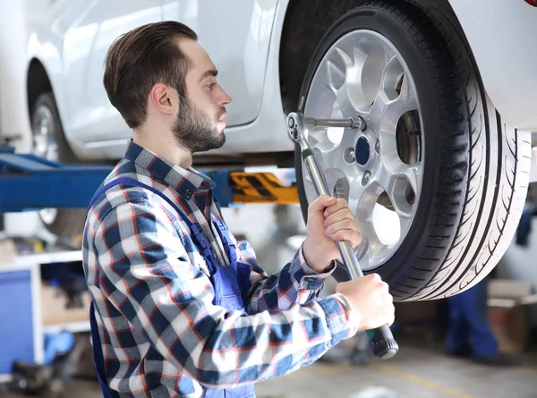 Jovem roda de mudança mecânica no serviço de pneus — Fotografia de Stock